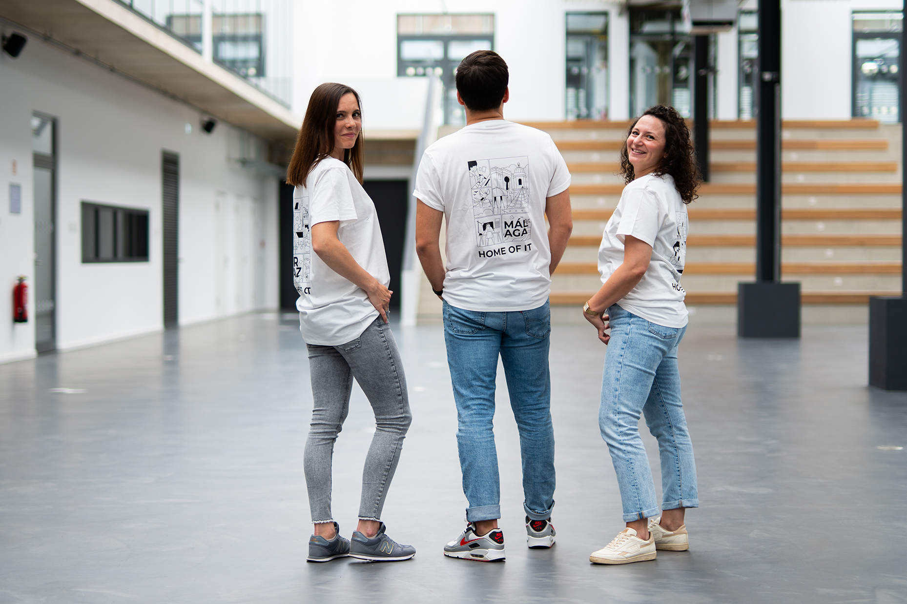 Three colleagues in white REWE digital t-shirts in the atrium