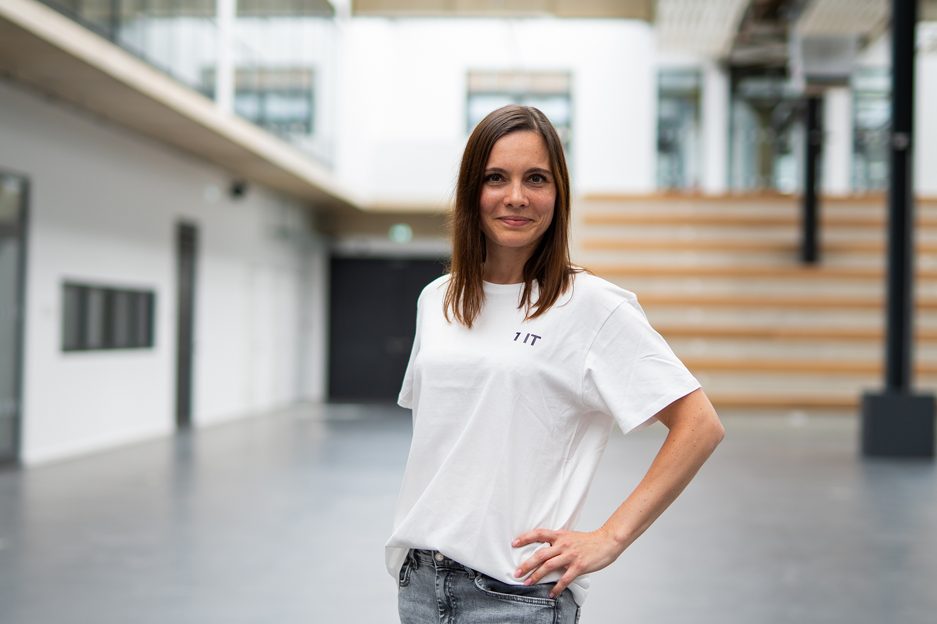Colleague in a white 1 IT t-shirt in the atrium of the office building